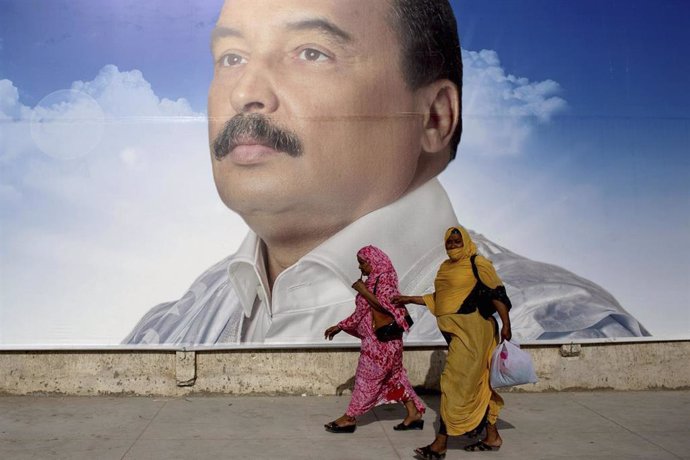 Mujeres pasean frente a una imagen de Mohamed Uld Abdelaziz