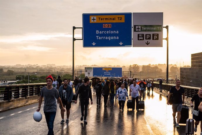 Alguns viatgers i manifestants caminen per la carretera d'accés a l'Aeroport de Barcelona-El Prat, en la jornada de concentració en protesta per la sentncia del Tribunal Suprem sobre el judici del procés, a Barcelona (Espanya), a 14 d'octubre de 2019.
