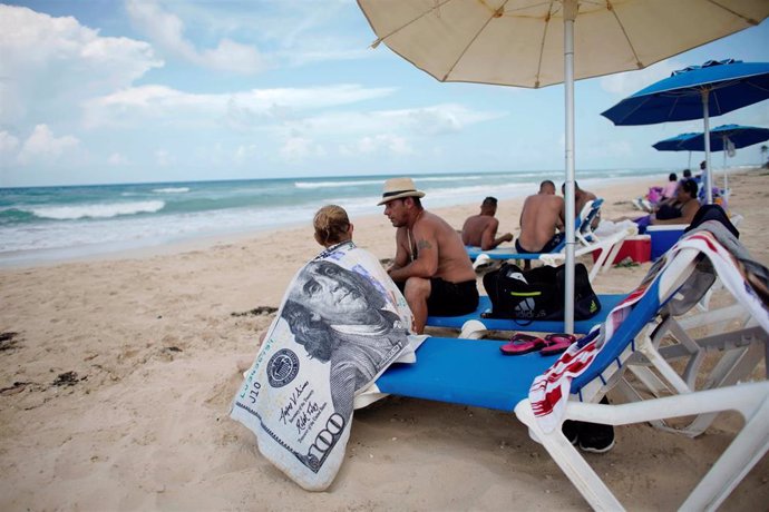 Una turista con una toalla con el símbolo de un billete de 100 dólares en una playa de Cuba
