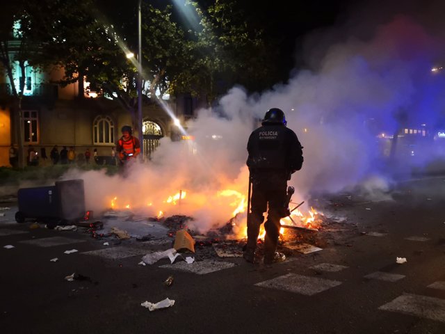 Un mosso d'Esquadra intenta apagar una hoguera durante disturbios de los CDR en Barcelona contra la sentencia del proceso independentista