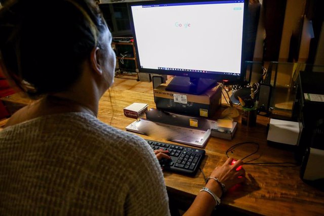 Una  mujer lee la pantalla de su ordenador, mientras trabaja en el despacho de su oficina.