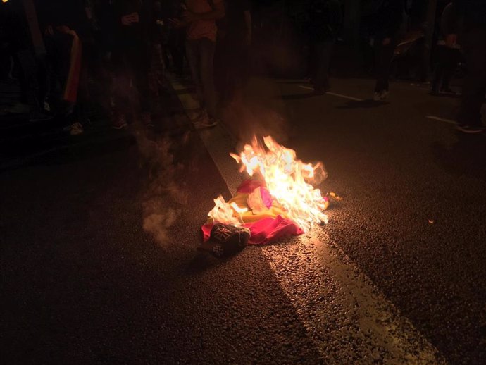Un grupo de antifascistas quema una bandera preconstitucional tras agredir a un ultra en disturbios a raíz de la sentencia contra el proceso independentista