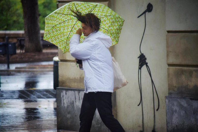 Una mujer camina por la calle sujetando su paráguas, movido por el viento, durante el temporal de gota fría que afecta a la zona de Levante, en Valencia (España) a 11 de septiembre de 2019.