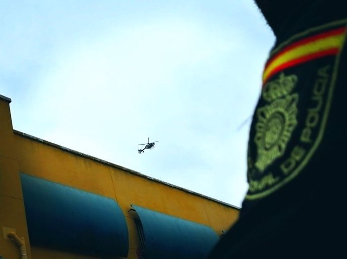 Parche de la Policía Nacional y un helicóptero sobrevolando el cielo.