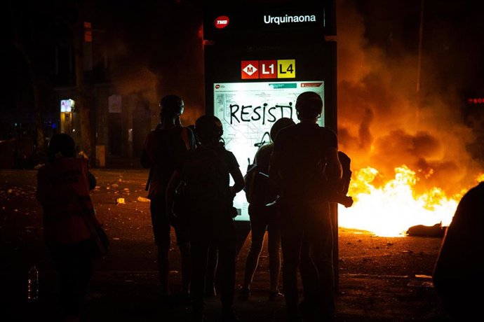 Varios manifestantes pintan el viernes letras en un panel luminoso durante los disturbios en la Plaza de Urquinaona y la Calle Roger de Lluría, en Barcelona a 18 de octubre de 2019.