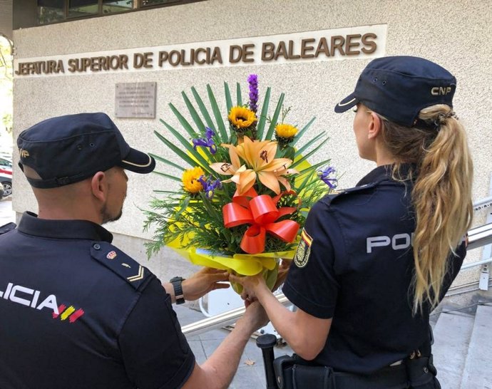 Dos agentes sostienen el ramo de flores depositado en la Jefatura Superior de Policía de Baleares.