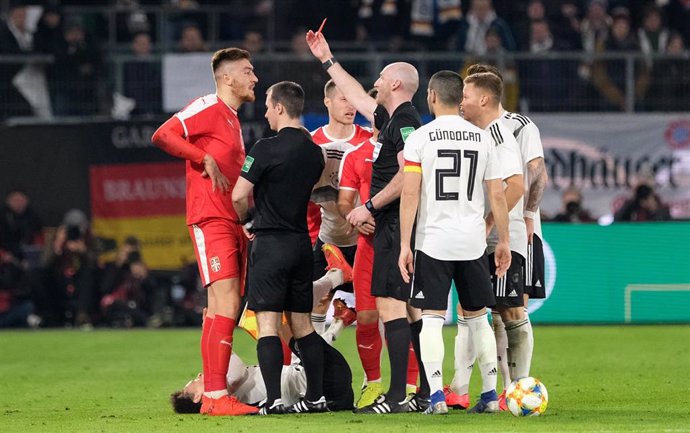 20 March 2019, Lower Saxony, Wolfsburg: Referee Bobby Madden (C) sends off Serbia's Milan Pavkov (L) after tackling Germany's Leroy Sane (bottom) during the international friendly soccer match between Germany and Serbia at the Volkswagen Arena. Photo: P