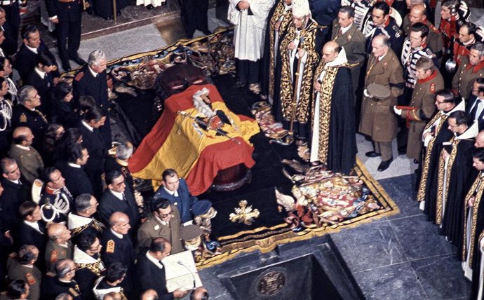 Vista del féretro, tapado por la bandera y el escudo de España durante el franquismo, que contiene el cuerpo del dictador Francisco Franco, antes de su sepultura en el interior de la Basílica del Valle de los Caídos durante su entierro tras su muerte tr