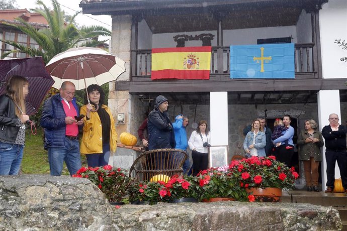 Varias personas con paraguas por la lluvia esperando la llegada de la Familia Real a Asiego, pueblo ejemplar de Asturias 2019, en Asturias (España) el 19 de octubre.