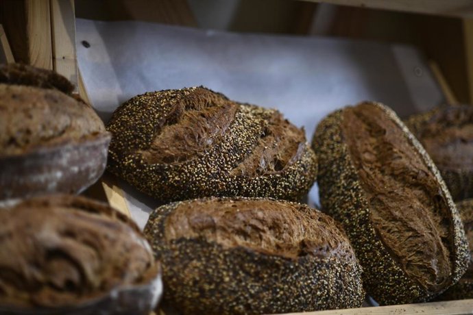 Unas hogazas de pan de semillas en el mostrador de una panadería.