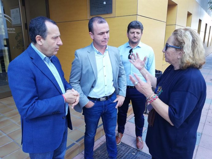 El líder del PSOE, José Luis Ruiz Espejo (i) y el secretario del PSOE de Manilva, Diego Jiménez, dialogan con una mujer