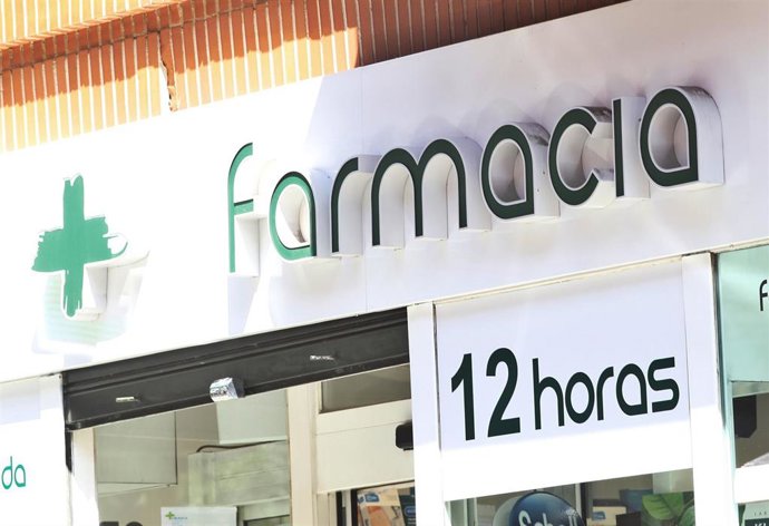 Puerta principal de una farmacia en la que se lee '12 horas'.
