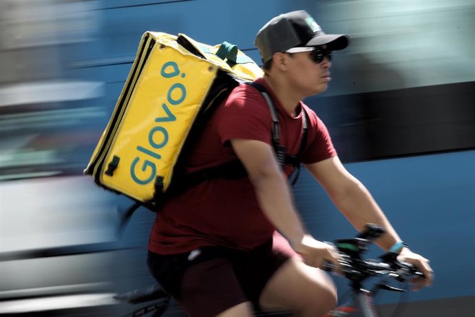 Un rider de la empresa de reparto de comida a domicilio Glovo, pasea por una calle de Madrid con su bicicleta.