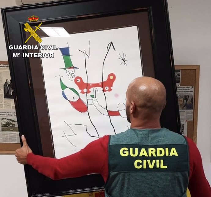 Un guardia civil sostiene una de las litografías robadas en Selva.