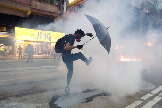 Un manifestante antigubernamental reacciona cuando la policía dispara gases lacrimógenos durante una marcha anunciada como una "llamada de emergencia" global para la autonomía, en Hong Kong, China