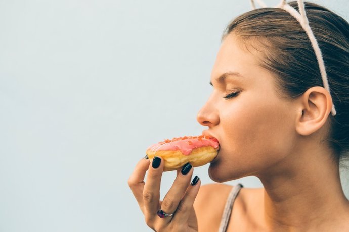 Sexy brunette lady eat sweet heart shaped donut.
