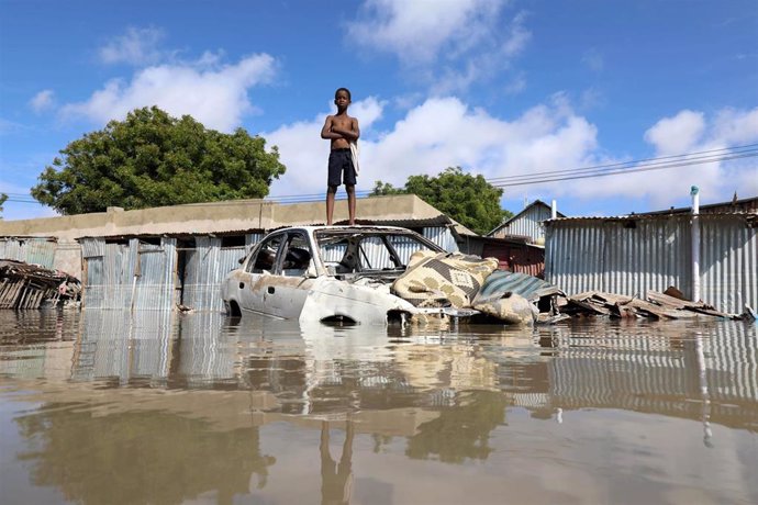 Un niño somalí parado sobre un coche destruido por las fuertes inundaciones en Mogadishu