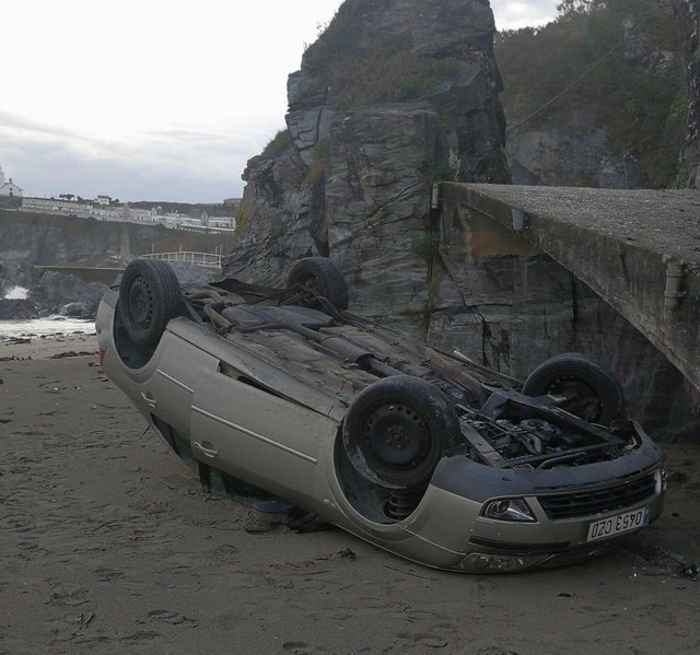 Vehículo volcado en la Playa Tercera de Luarca.