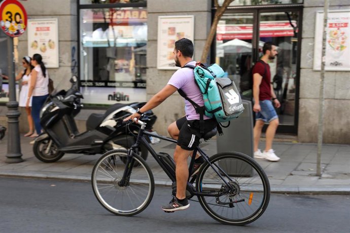 Fotografía de un repartidor de la empresa de reparto Deliveroo transitando en bicliceta por una calle del centro de Madrid.