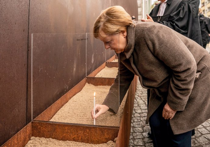09 November 2019, Berlin: German Chancellor Angela Merkel, lights a candle in the sand at the Berlin Wall Memorial on Bernauer Street to mark the 30th anniversary of the fall of the Berlin Wall. Photo: Michael Kappeler/dpa