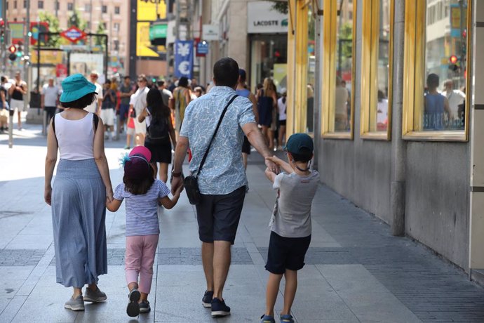 Una família passeja de la m per un carrer de Madrid.