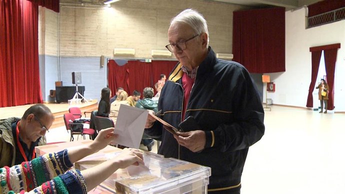 Un elector deposita su voto en una urna en un colegio electoral de Extremadura.
