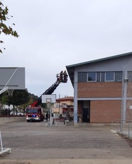 Los bomberos retiran lazos amarillos de la fachada del Centre Cívic al Cooperativa en Sarrià de Ter (Girona).