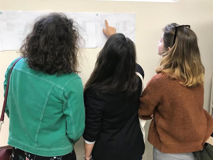 Una jóvenes comprueban su mesa electoral para votar