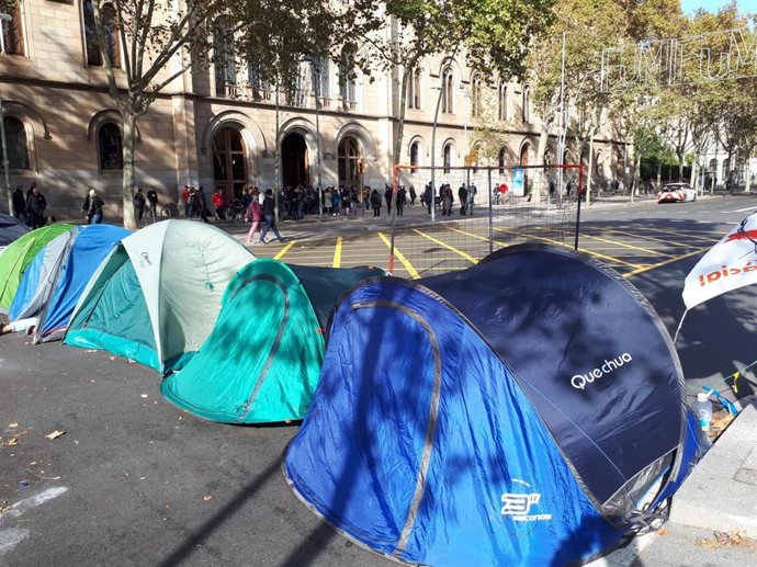 Jóvenes acampados en la plaza Universitat de Barcelona cerca de una cola de votantes el día de las elecciones generales del 10 de noviembre de 2019