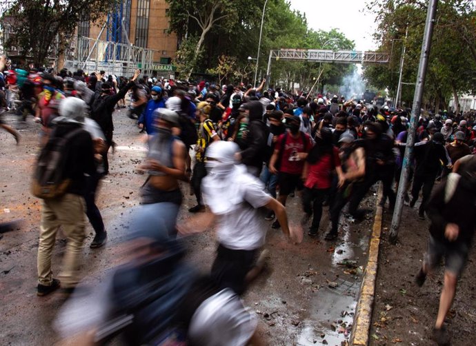 08 November 2019, Chile, Santiago: Protesters run during clashes with riot police following anti-government protest in Plaza Baquedano. Photo: Adrian Manzol/ZUMA Wire/dpa