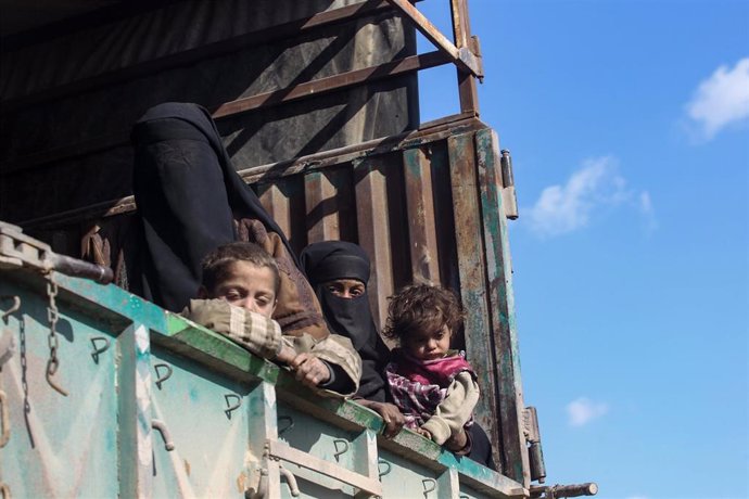 Mujeres y niños sobre un camión durante una evacuación (imagen de archivo)