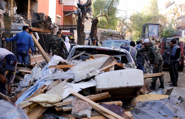 Syrian police stand outside a damaged building in Mezzah, Damascus, Syria