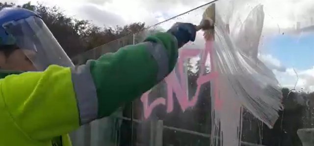 Imagen de un operario de limpieza eliminando las pintadas realizadas en los vinilos del viaducto de la calle Bailén.