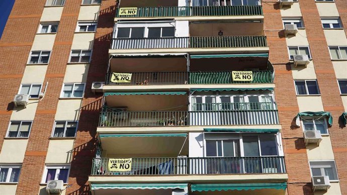 Imagen de un bloque de viviendas con carteles en apoyo al cierre del vertedero en Alcalá.