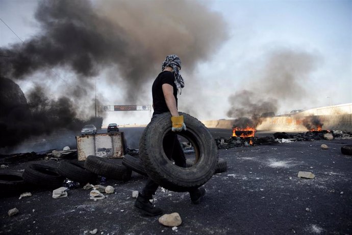 Un hombre con un neumático durante el bloqueo de una carretera en Líbano durante las manifestaciones contra el Gobierno