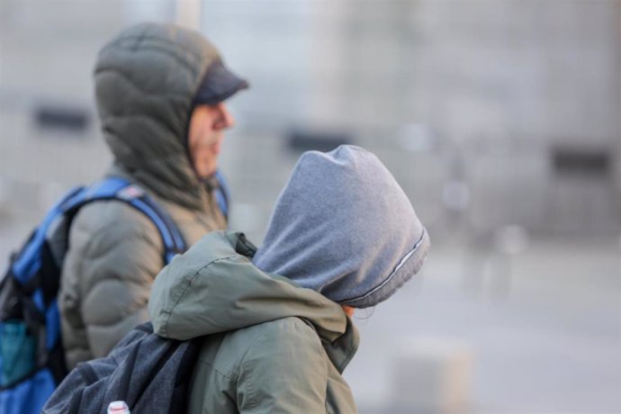 Dos jovenes se protegen del frío con abrigos y gorros mientras pasean durante un día de viento por Madrid (España), a 8 de noviembre de 2019.