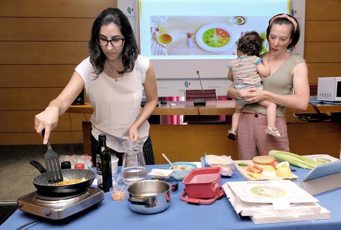 La nutricionista, Laura Álvarez de Nestlé, explica a una madre con su bebé como realizar una receta.