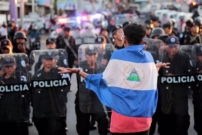 Manifestante antigubernamental delante de Policías antidisturbios en Managua