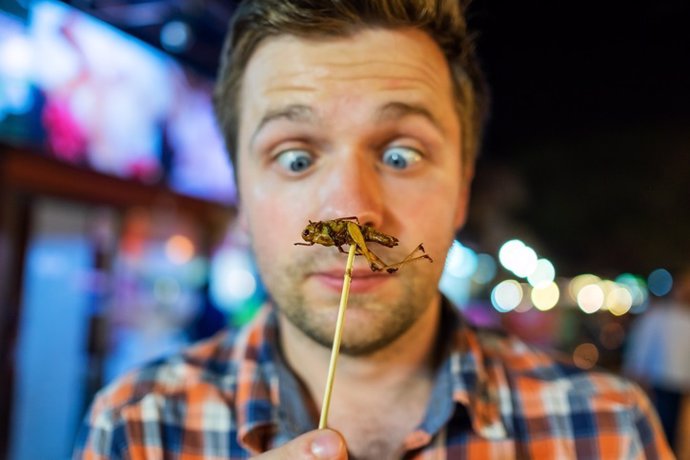 Hombre decidiendo comerse un insecto.