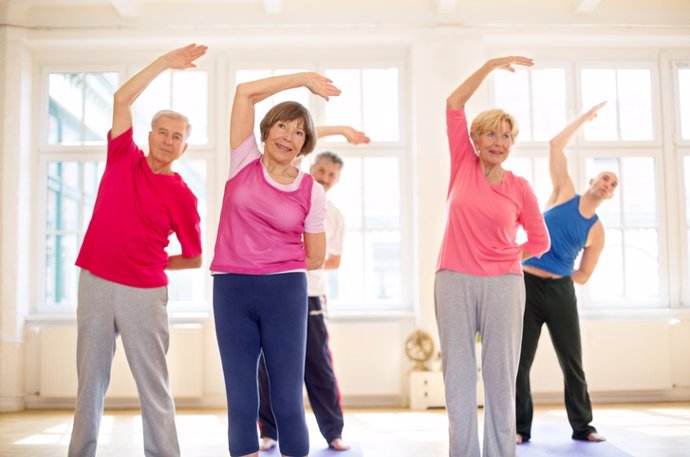 Senior people doing stretches together at gym