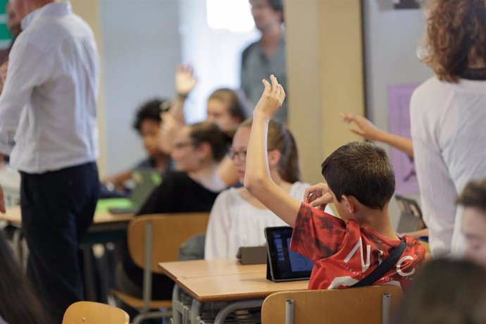 Un niño levanta la mano en un aula