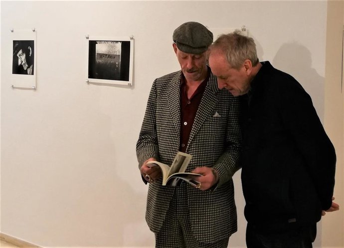 El fotógrafo Steve Pyke y el escritor Timothy O'Grady ojean el libro 'Sabía leer el cielo', ante algunas imágenes de la exposición del mismo nombre, que se puede ver en el Ayuntamiento de Logroño.