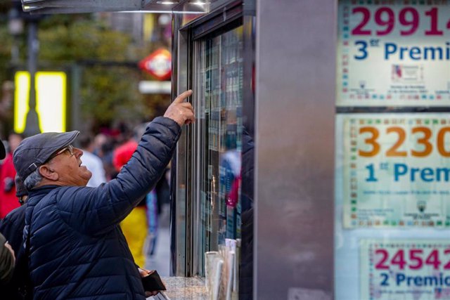 Un hombre señala el décimo de Lotería de Navidad que quiere comprar en una Administración en la plaza de Puerta del Sol, en Madrid.