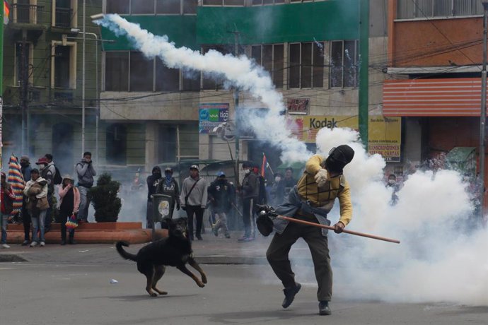 13 November 2019, Bolivia, La Paz: A supporter for the former Bolivian President Morales hurls a tear gas canister back against police during clashes following a mass protests demanding the the resignation of current interim President Jeanine Anez. Phot