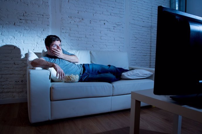Man watching television with remote control surprised disbelief face expression