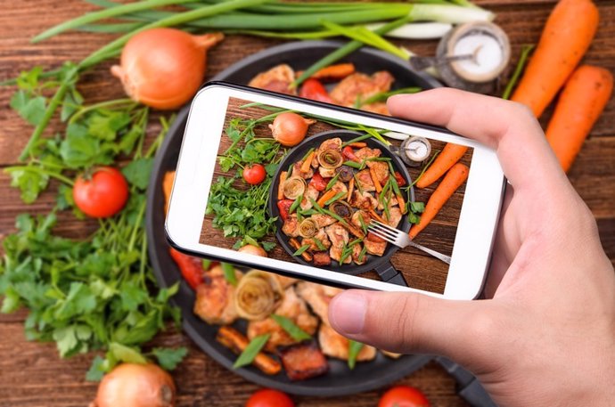 Hand using a smartphone to take photo of their meal