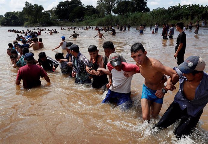 Grupo de migrantes centroamericanos cruzando un río a su paso por Ciudad Hidalgo, México.
