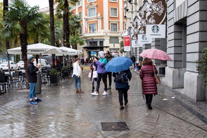 Varias personas pasean por la calle con un paraguas debido a la lluvia durante el peor temporal del otoño del 2019 en España en el que se verán afectadas 37 provincias avisadas por viento, nieve, oleaje o lluvia, en Madrid (España),  a 14 de noviembre d