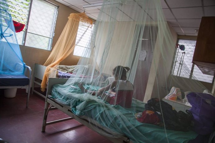Una niña sentada en una cama con mosquitero en Nicaragua