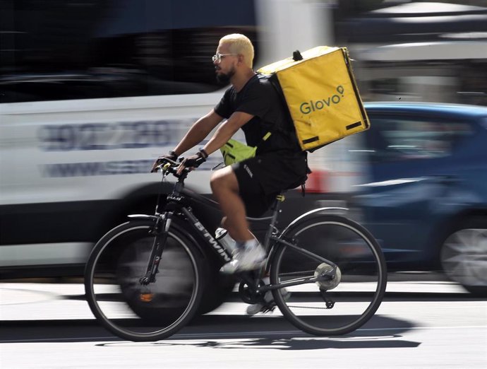 Un rider de la empresa de reparto de comida a domicilio Glovo, pasea por una calle de Madrid con su bicicleta.